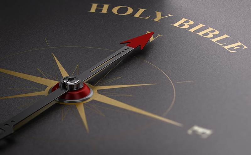 Eine genordete Kompassnadel, die auf Holy Bible zeigt