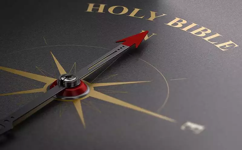 Eine genordete Kompassnadel, die auf Holy Bible zeigt