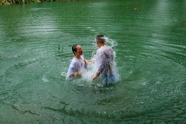 Zwei Menschen stehen im Wasser eines Teiches und denken über das Geheimnis der Dreifaltigkeit nach.