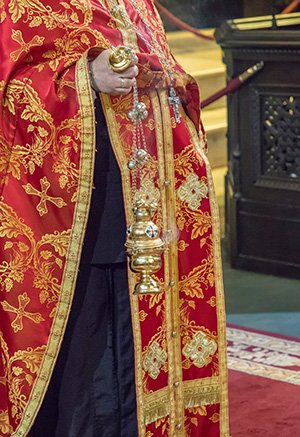 Ein Mann in einem rot-goldenen Gewand hält eine Kerze.